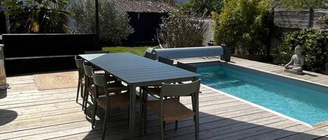 A wooden deck with a pool, a table, and chairs.