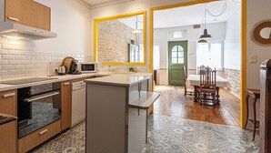 Una cocina moderna con armarios blancos, horno empotrado y un espejo grande con marco amarillo.
