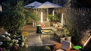 Un patio con pared de piedra, mobiliario exterior y plantas en macetas.