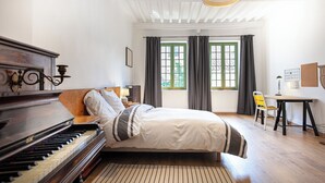 Un dormitorio con un piano, una cama, un escritorio y una silla.