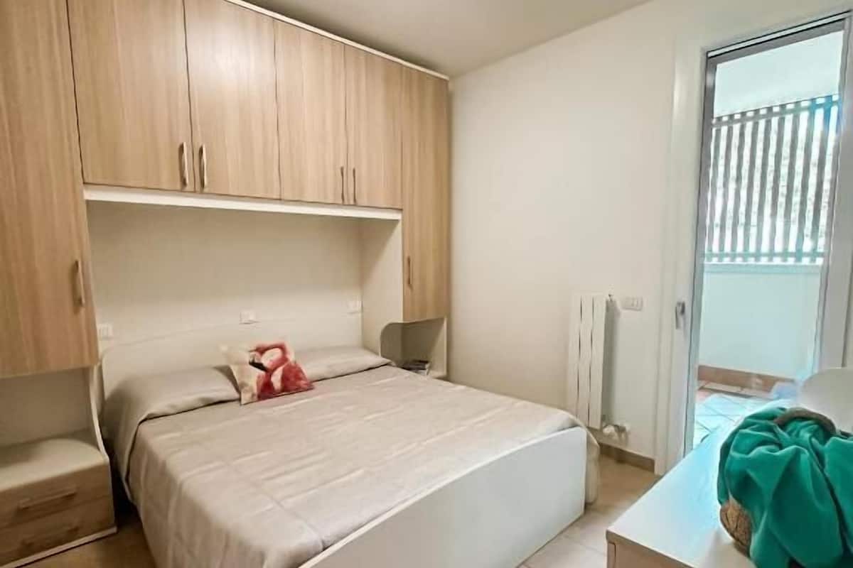 Un dormitorio con cama, cómoda, mesita de noche y ventana con persianas.