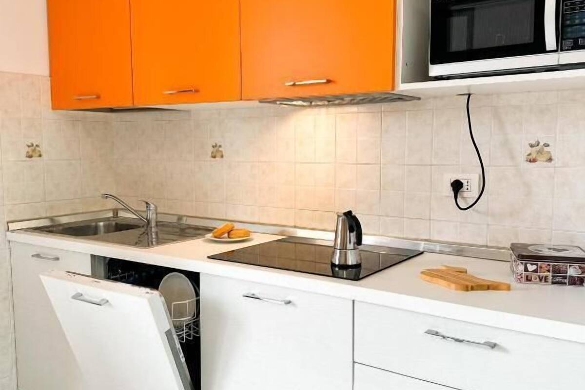 Una cocina con gabinetes color naranja, un microondas, un fregadero y un lavavajillas.