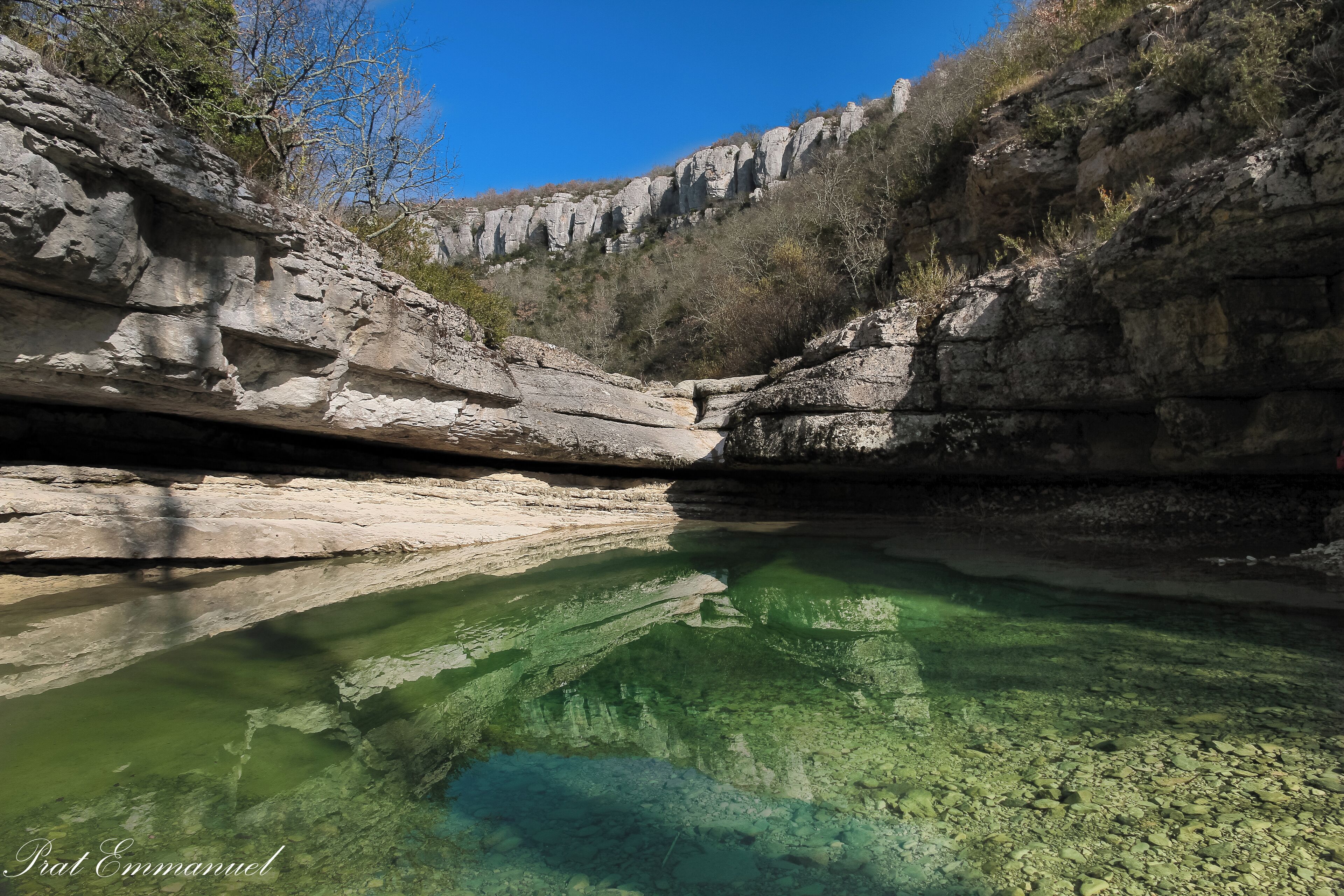 A natural rocky landscape with a clear water body reflecting the surrounding cliffs.