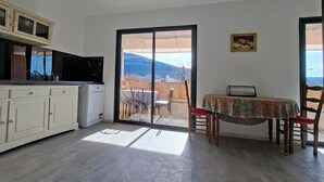 Una cocina con lavavajillas, una mesa de comedor con sillas y vistas a montañas a través de un ventanal corredero.