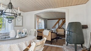 A cozy dining area with a wooden table set for two, a chandelier, and a stone fireplace. - The Cozy Cottage – Charming Holiday Home near the North Sea (Hirtshals)