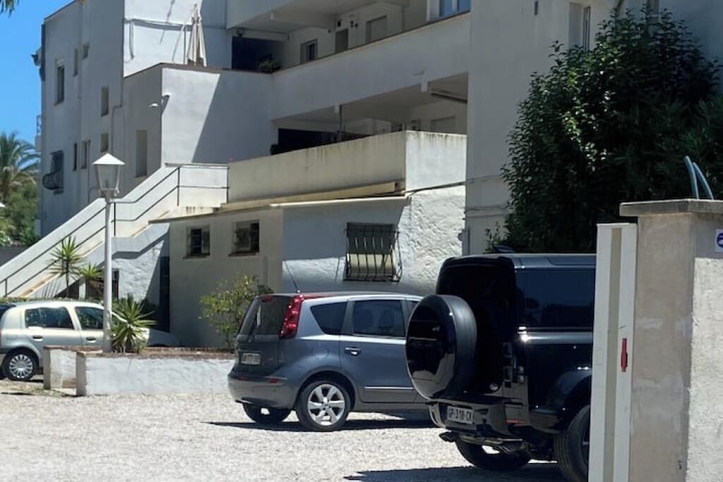 A multi-story building with a parking area.