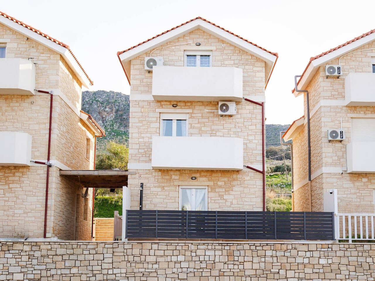 Un immeuble résidentiel de deux étages, doté d’une façade en pierre, de balcons et de climatiseurs.