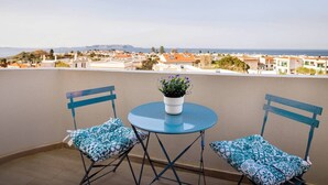 A balcony with two chairs and a table, overlooking a coastal town. - Spacious Gournes Home for 7 | 2.5 Baths (Gournes)