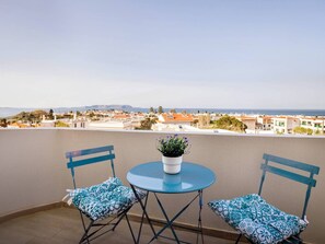Ein Balkon mit zwei Stühlen und einem Tisch, mit Blick auf eine Küstenstadt.
