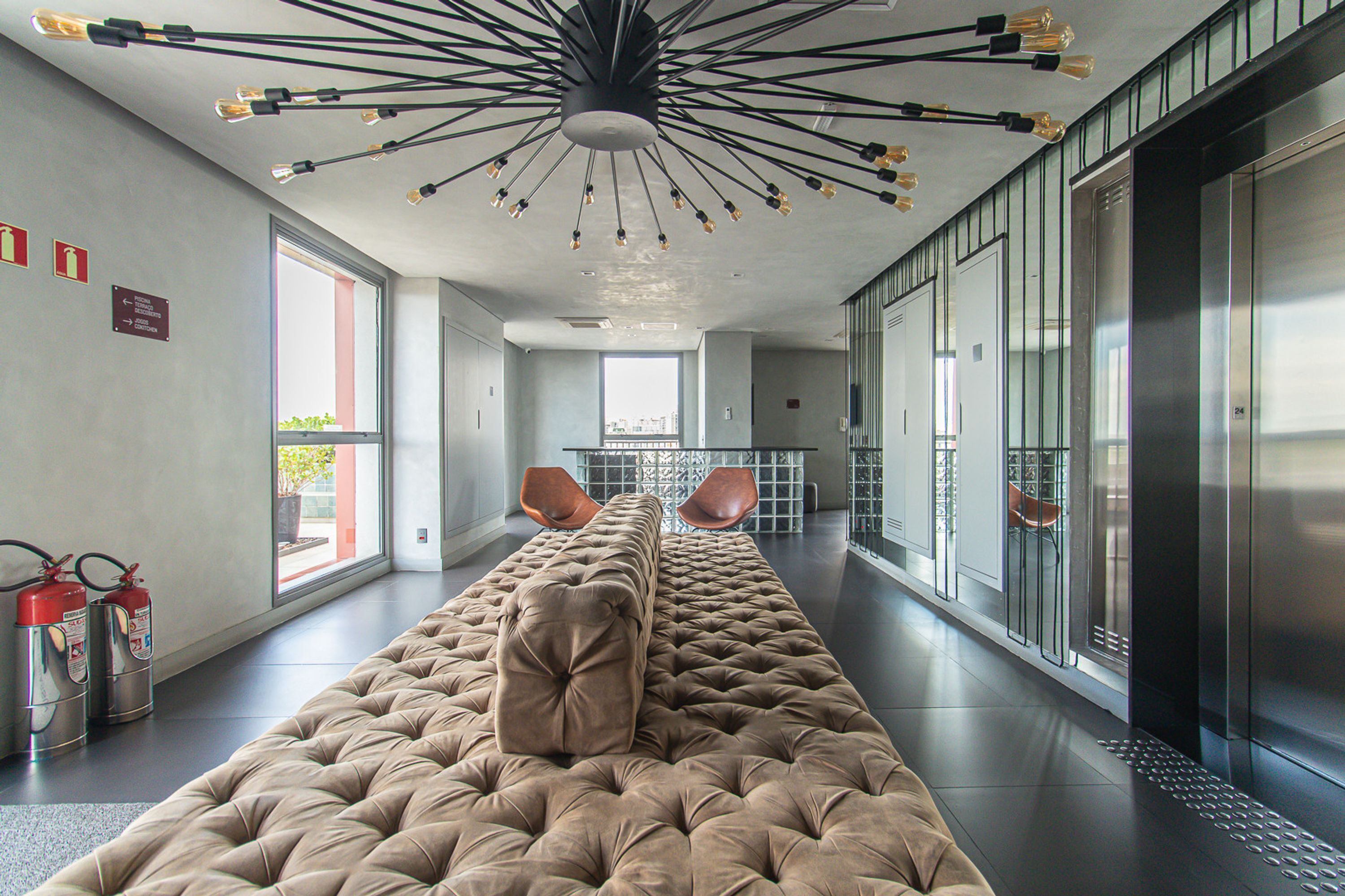 Een moderne lobby met een gestoffeerde bank, een brandblusser en een lift.