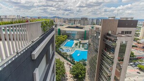 Ein Hochhaus mit Dachgarten, einem Poolkomplex und Blick auf die Skyline im Hintergrund.