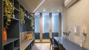 Ein moderner Büroarbeitsplatz mit einem langen Tisch, Stühlen, einer Couch und Regalen mit Pflanzen.