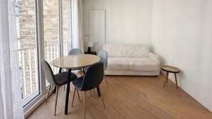 Ein Zimmer mit einem runden Tisch, zwei Stühlen, einem Sofa und einem kleinen Beistelltisch.