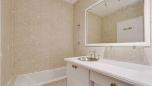 Ein Badezimmer mit Badewanne, Waschbecken und Spiegel.