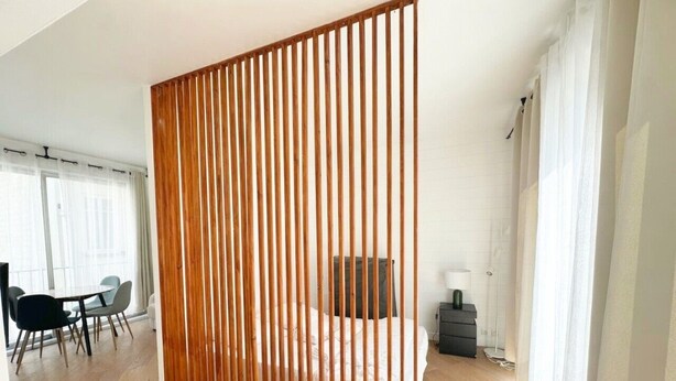 Ein modernes Hotelzimmer mit einer Holzwand, einem Bett, einem Schreibtisch und einem Stuhl.