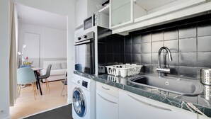 Eine kompakte Küche mit integriertem Waschmaschine, Spüle und Essbereich mit Tisch und Stühlen.