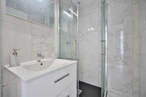 A modern bathroom with a white vanity, a glass shower enclosure, and marble walls. - 1D#Studio 2 pers#Bon Marché#St Germain#Paris 6 (Paris)