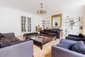 A spacious living room with a large sofa set, a coffee table, and a fireplace. - Appartement 4 Chambres/4 SDB/Paris 17 (Paris)