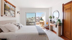 Une chambre avec un lit, une vue sur la ville, un balcon et une porte en bois.