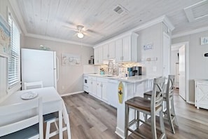 A kitchen with white cabinetry, a wooden dining table, and a ceiling fan. - 🐾Pet Friendly | Community Pool + Walk to Beach | Sea and Sun Unit 6🐾 (Gulf Shores)