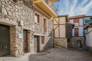 Une rue étroite bordée d’immeubles en pierre, avec un balcon et une porte surmontée d’un portail en métal.