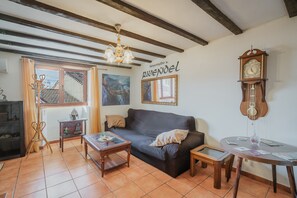 A living room with a sofa, coffee table, and a wall-mounted clock.