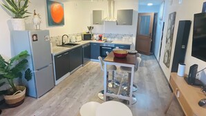 Una cucina funzionale con elettrodomestici moderni, una zona pranzo con un piccolo tavolo e sedie, e un divano rosso in primo piano.