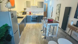 A modern kitchen with a central island, white cabinets, and a wooden floor. - Mirepoix 4 star apartment (Mirepoix)
