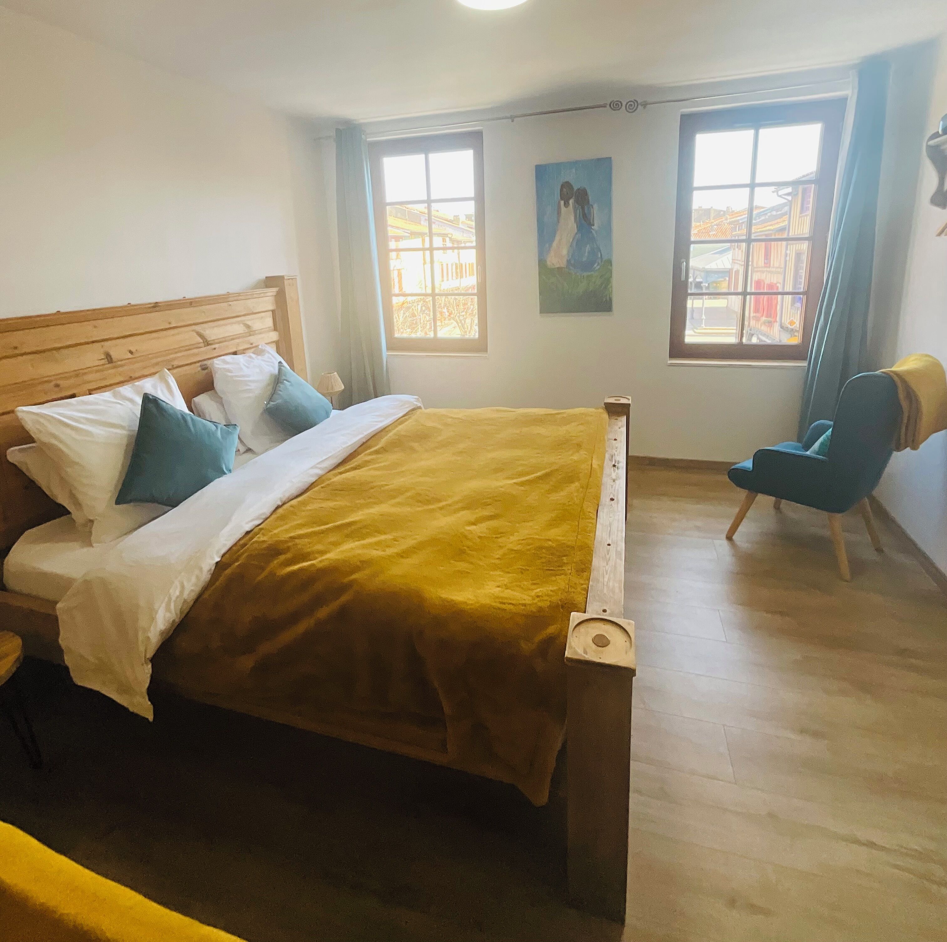 A bedroom with a wooden bed, a chair, and two windows.