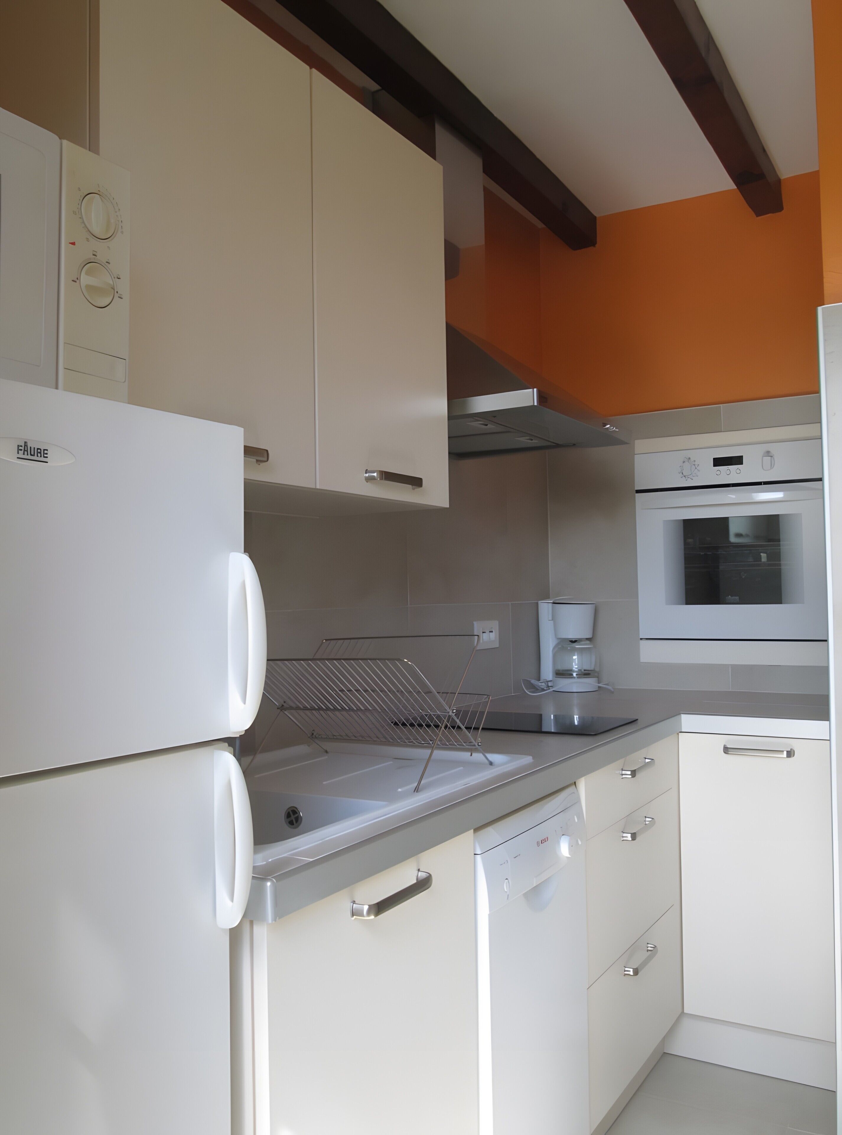 A kitchen with white cabinets, a built-in oven, and a coffee maker.