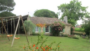 Ein Haus mit Garten, Schaukel und Steinofen.