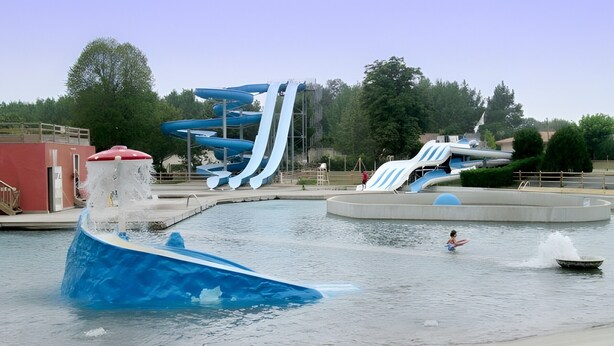 Ein Wasserpark mit einer großen, blauen Rutsche, einem Wellenbecken und einem kleinen Boot.