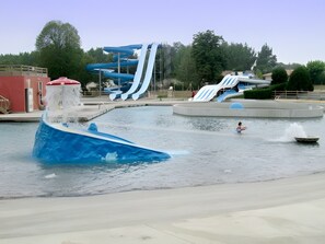 A water park with a large blue water slide, a wave pool, and a small boat. - Holiday Home "Charming Country Cottage" with Private Garden (Gondrin)