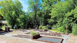 Ein Park mit einem Spielplatz, gepflasterten Wegen und einer Holzschaukel.