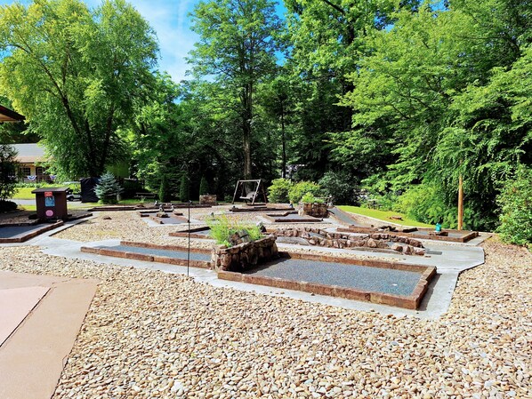 Un parc doté d’une aire de jeux, de sentiers en pierre et d’une balançoire en bois.