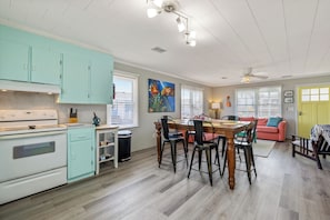 Une cuisine équipée d’une cuisinière, de placards et d’un coin repas avec des chaises et une table.