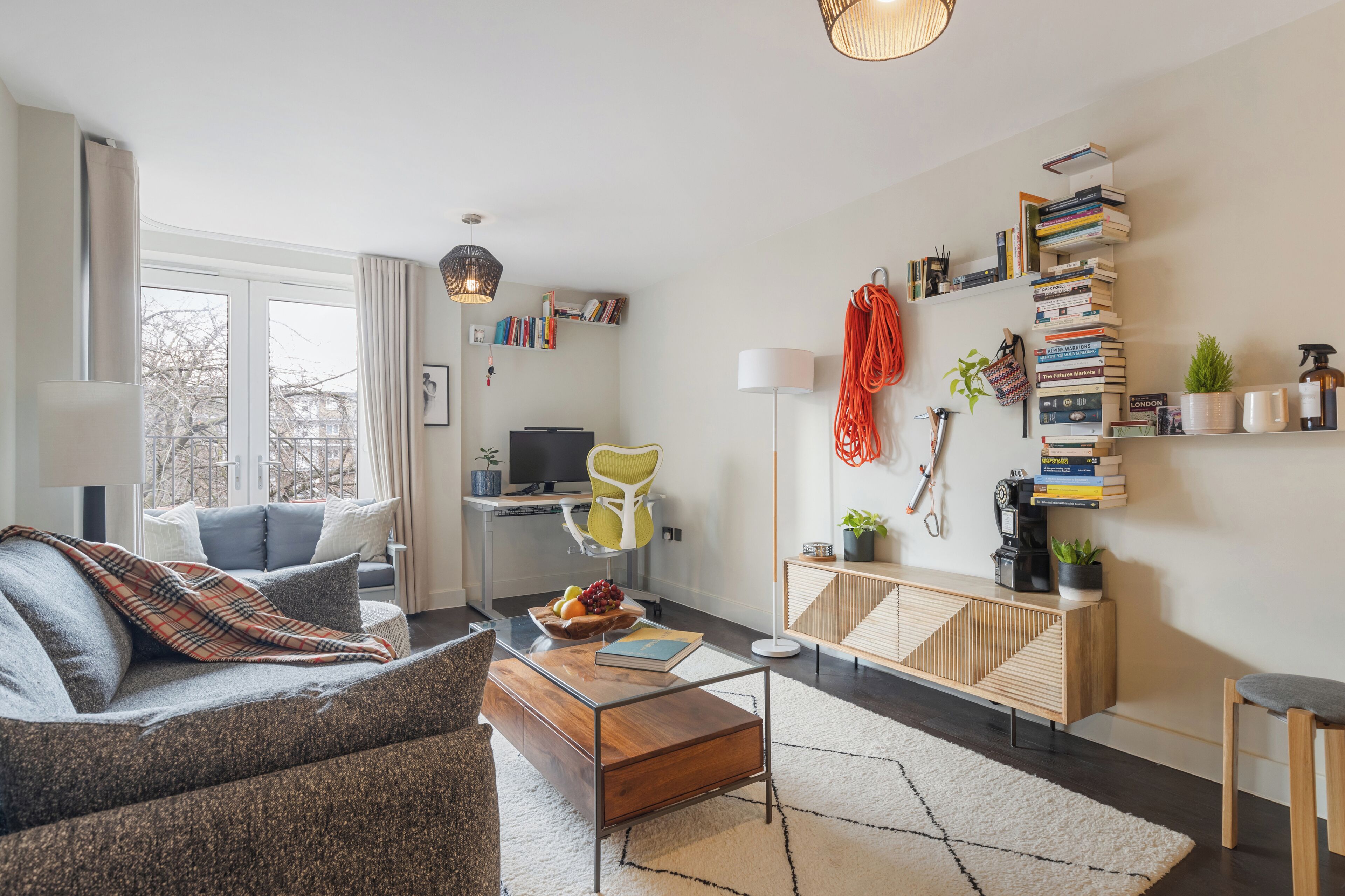 Uma sala de estar moderna com um sofá, mesa de centro e uma estante cheia de livros.