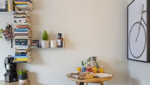 Una habitación acogedora con una mesa de madera, dos sillas, una estantería, una planta en maceta y un cuadro de una bicicleta en la pared.