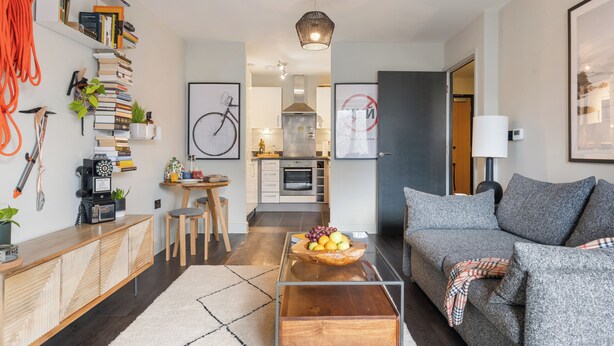 Una sala de estar moderna con un sofá, una mesa de centro y una estantería llena de libros y objetos decorativos.