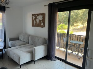A modern living room with a sofa, a world map artwork, and a balcony with a table and chairs. - Propriano lovely 2-room apartment 46m2 with terrace&balcony (Propriano)