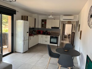 A modern kitchen with a refrigerator, microwave, and oven. There is a dining area with two chairs and a table. - Propriano lovely 2-room apartment 46m2 with terrace&balcony (Propriano)
