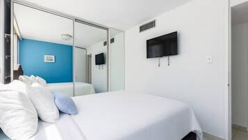 Un dormitorio con cama, televisor montado en la pared y puerta corrediza de vidrio que da al baño.