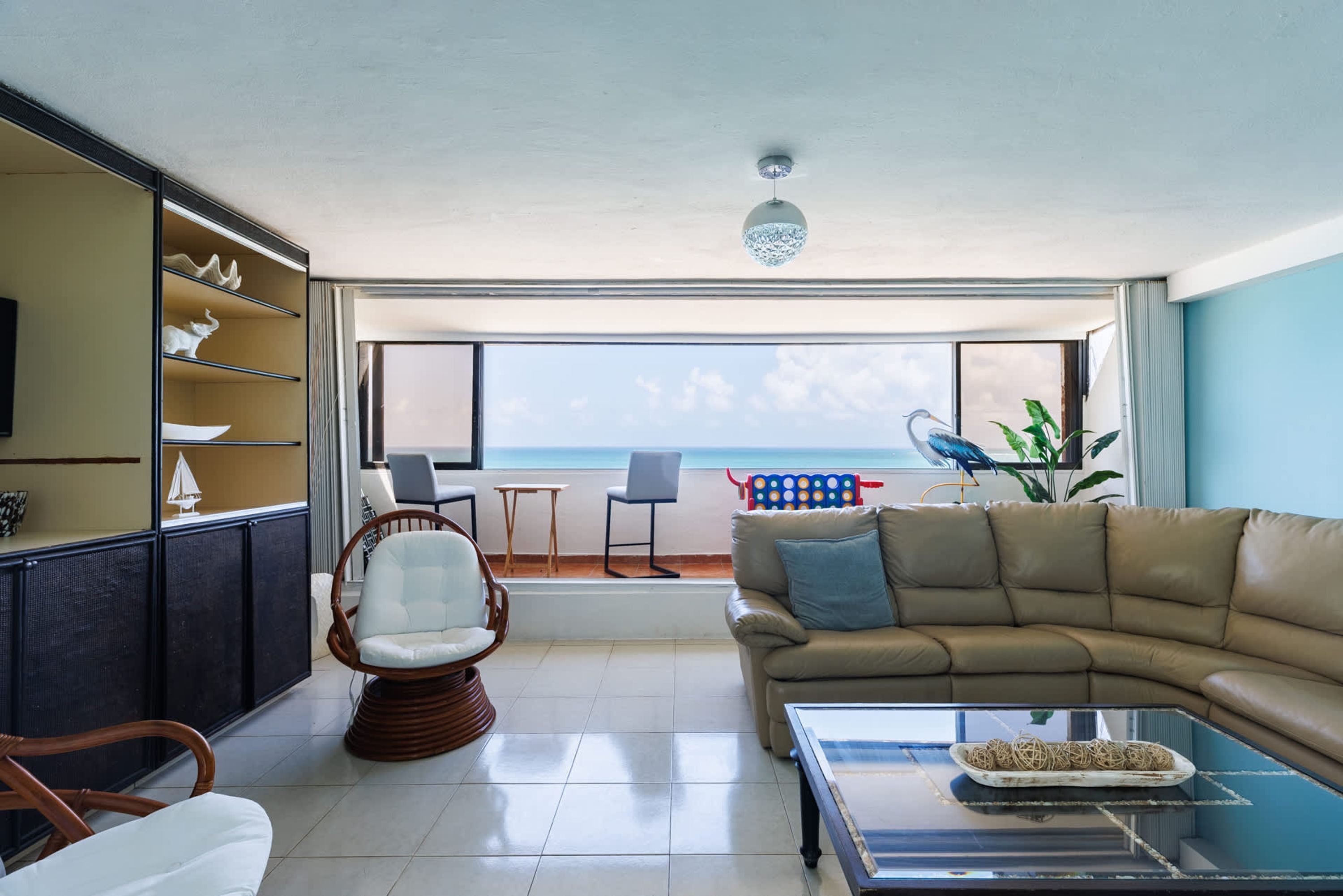 Un salón con sofá, sillas, mesa de centro y vista al mar.