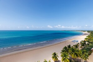 A beach with clear blue water, sandy shore, and palm trees. - Isla Verde Oceanview 4BR With Private Beach Access (Carolina)