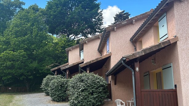 A two-story building with a gravel driveway, a wooden fence, and a large tree in the background. - Le soleil d'eau 3 villa with terrace, parking (Meyras)