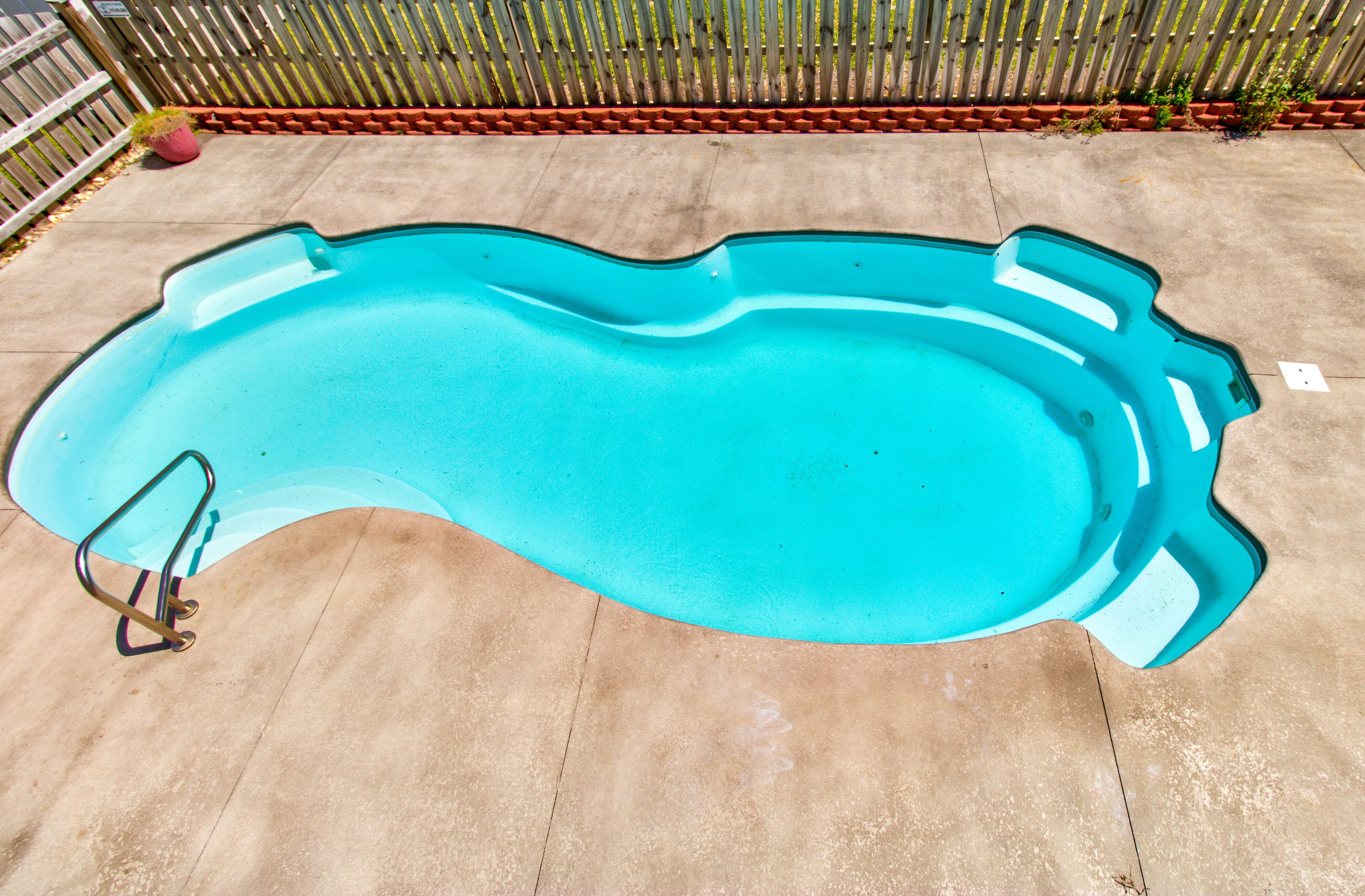 Une piscine à bordures courbes, entourée d’une terrasse en béton.