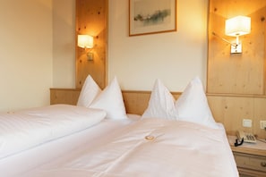 A hotel room with a bed, two bedside tables, a nightstand, and two wall-mounted lamps. - Landhotel Hoftaverne Atzmüller (Oberneukirchen)