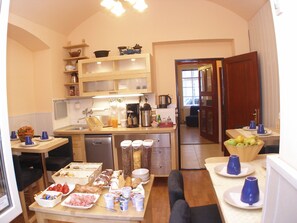 A compact kitchen with a dining area, equipped with basic appliances and a variety of food items. - Aparthotel Davids (Prague)