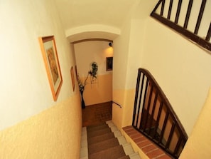 A staircase with a wooden handrail, beige walls, and a small plant on the landing. - Aparthotel Davids (Prague)