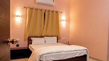 Un dormitorio con cama, cortinas, luces empotradas en la pared, aire acondicionado y una puerta con cerradura.